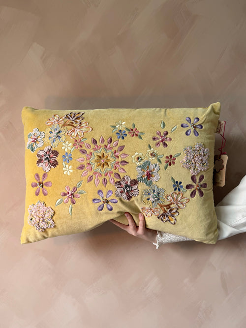 Geel kussen met geborduurde bloemen