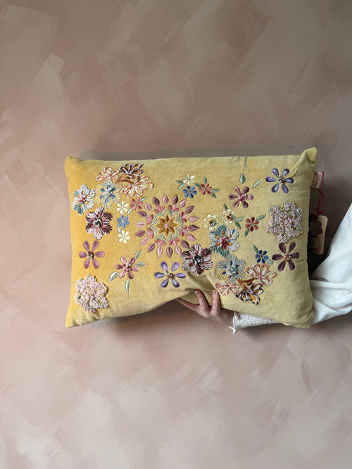 Geel kussen met geborduurde bloemen